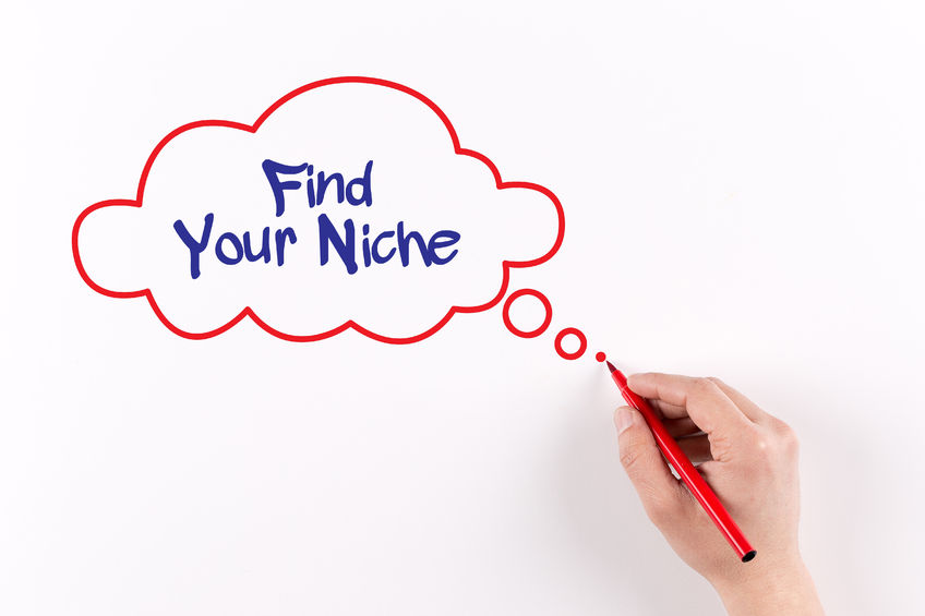 Hand writing "find your niche" in a thought bubble on whiteboard